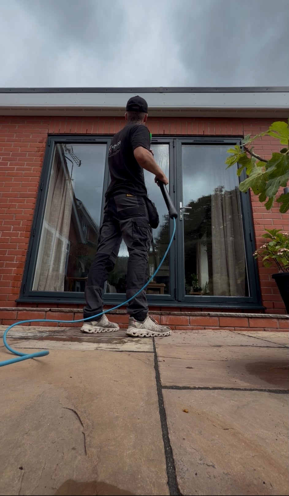 Operator washing conservatory doors on a brick house