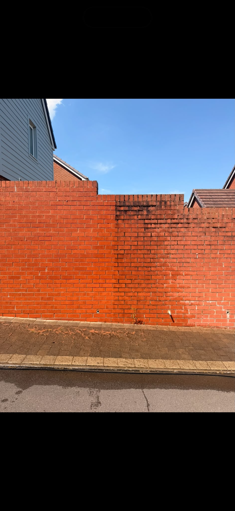 Red brick wall half cleaned during a pressure wash, clean brick beside remaining dirt